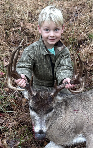 Young boy holds deer by the antlers